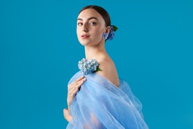 Photo of Portrait of beautiful woman with hortensia flowers and cloth on blue background
