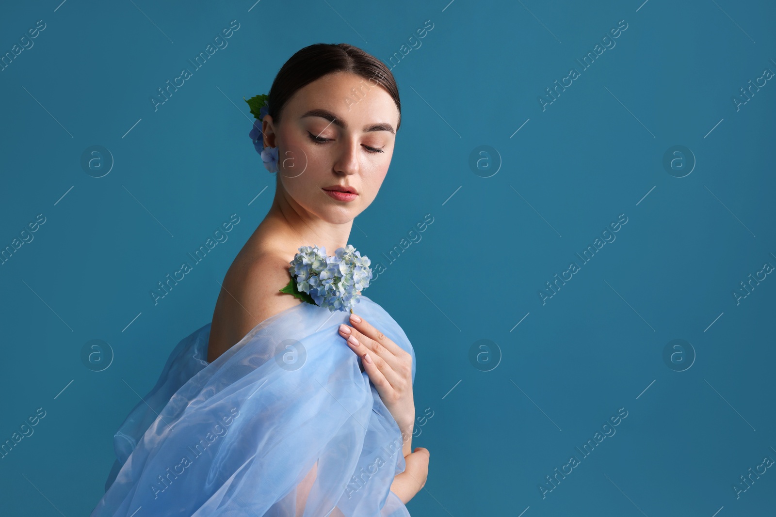 Portrait of beautiful woman with hortensia flowers and cloth on blue background. Space for text Photo of Portrait of beautiful woman with hortensia flowers and cloth on blue background. Space for text