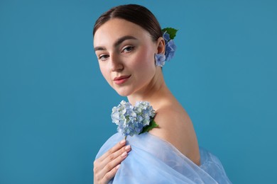 Photo of Portrait of beautiful woman with hortensia flowers and cloth on blue background