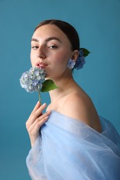 Photo of Portrait of beautiful woman with hortensia flowers and cloth on blue background