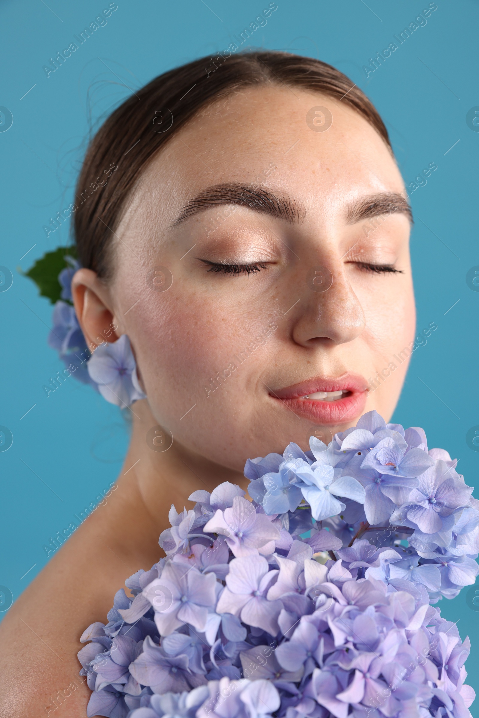Photo of Portrait of beautiful woman with hortensia flowers on blue background