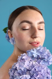 Photo of Portrait of beautiful woman with hortensia flowers on blue background