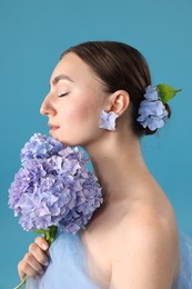 Photo of Portrait of beautiful woman with hortensia flowers on blue background