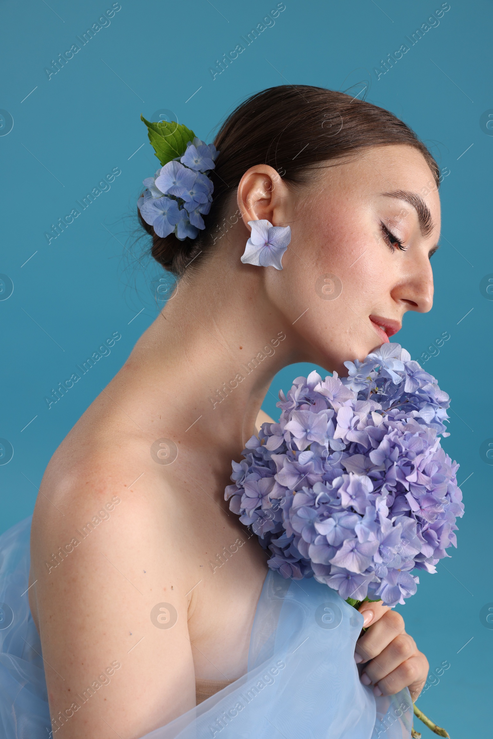 Photo of Portrait of beautiful woman with hortensia flowers on blue background