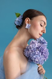 Photo of Portrait of beautiful woman with hortensia flowers on blue background