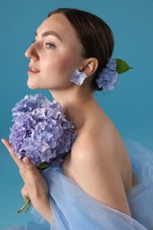 Photo of Portrait of beautiful woman with hortensia flowers on blue background