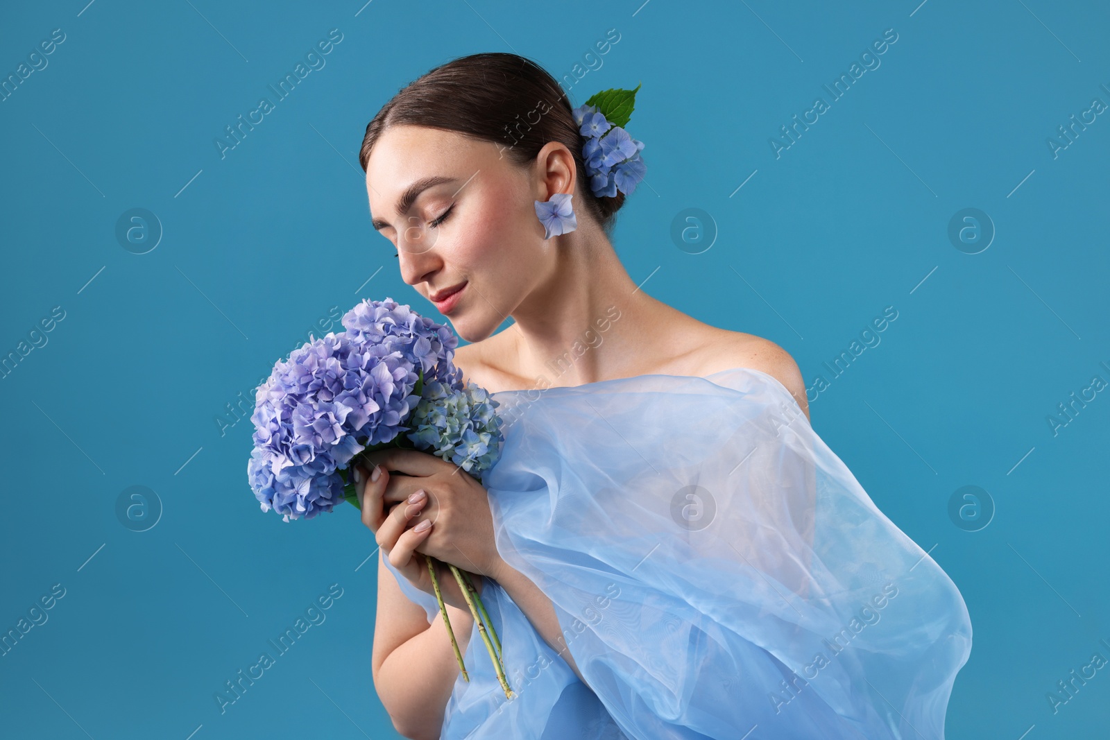 Photo of Portrait of beautiful woman with hortensia flowers on blue background