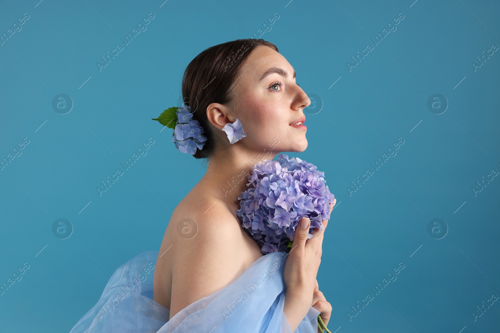 Photo of Portrait of beautiful woman with hortensia flowers on blue background