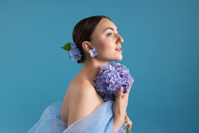 Photo of Portrait of beautiful woman with hortensia flowers on blue background