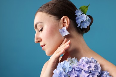 Photo of Beautiful young woman with hortensia flowers on blue background