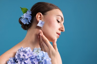 Photo of Beautiful young woman with hortensia flowers on blue background