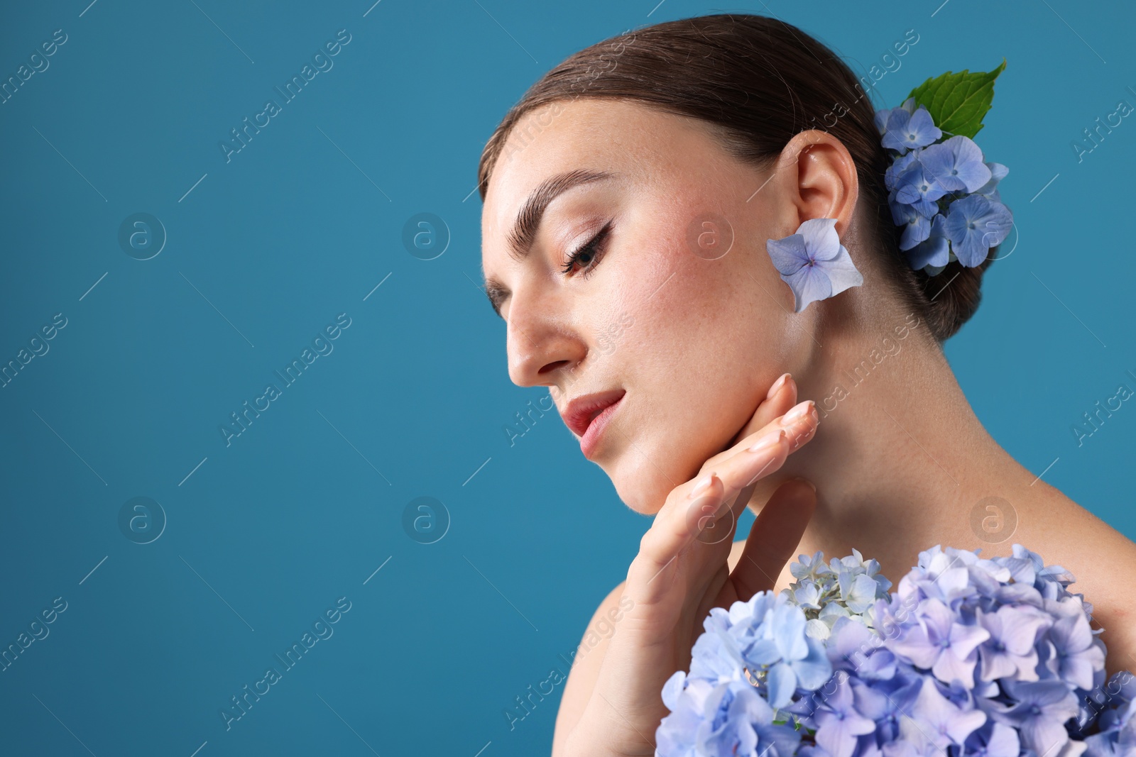 Photo of Beautiful young woman with hortensia flowers on blue background. Space for text