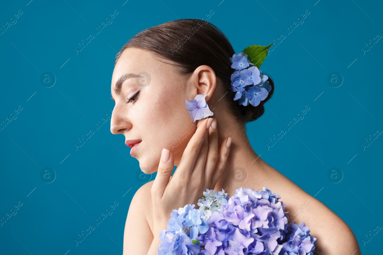 Photo of Beautiful young woman with hortensia flowers on blue background