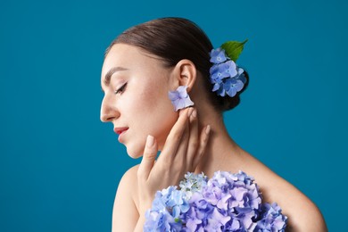 Photo of Beautiful young woman with hortensia flowers on blue background