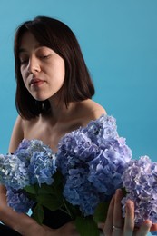 Photo of Beautiful young woman with hortensia flowers on light blue background