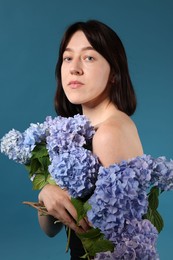 Photo of Beautiful young woman with hortensia flowers on blue background