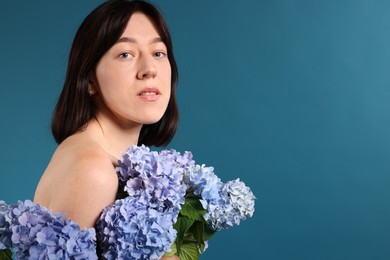 Photo of Beautiful young woman with hortensia flowers on blue background. Space for text