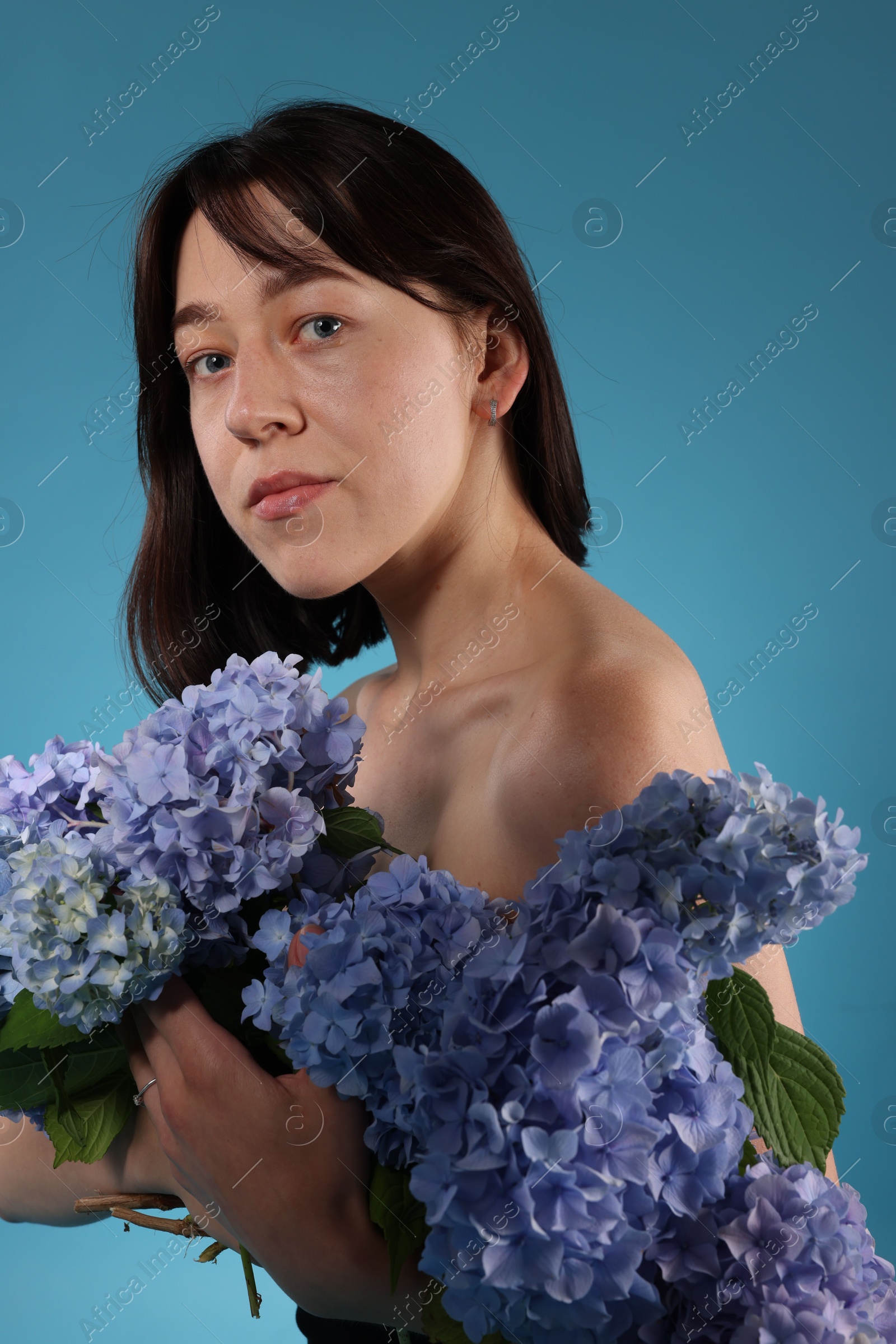 Photo of Beautiful young woman with hortensia flowers on blue background