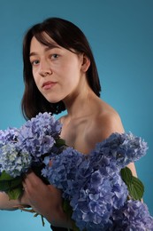 Photo of Beautiful young woman with hortensia flowers on blue background