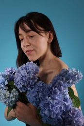 Photo of Beautiful young woman with hortensia flowers on blue background