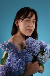 Photo of Beautiful young woman with hortensia flowers on blue background
