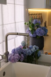 Photo of Bouquets of beautiful blue hortensia flowers in kitchen