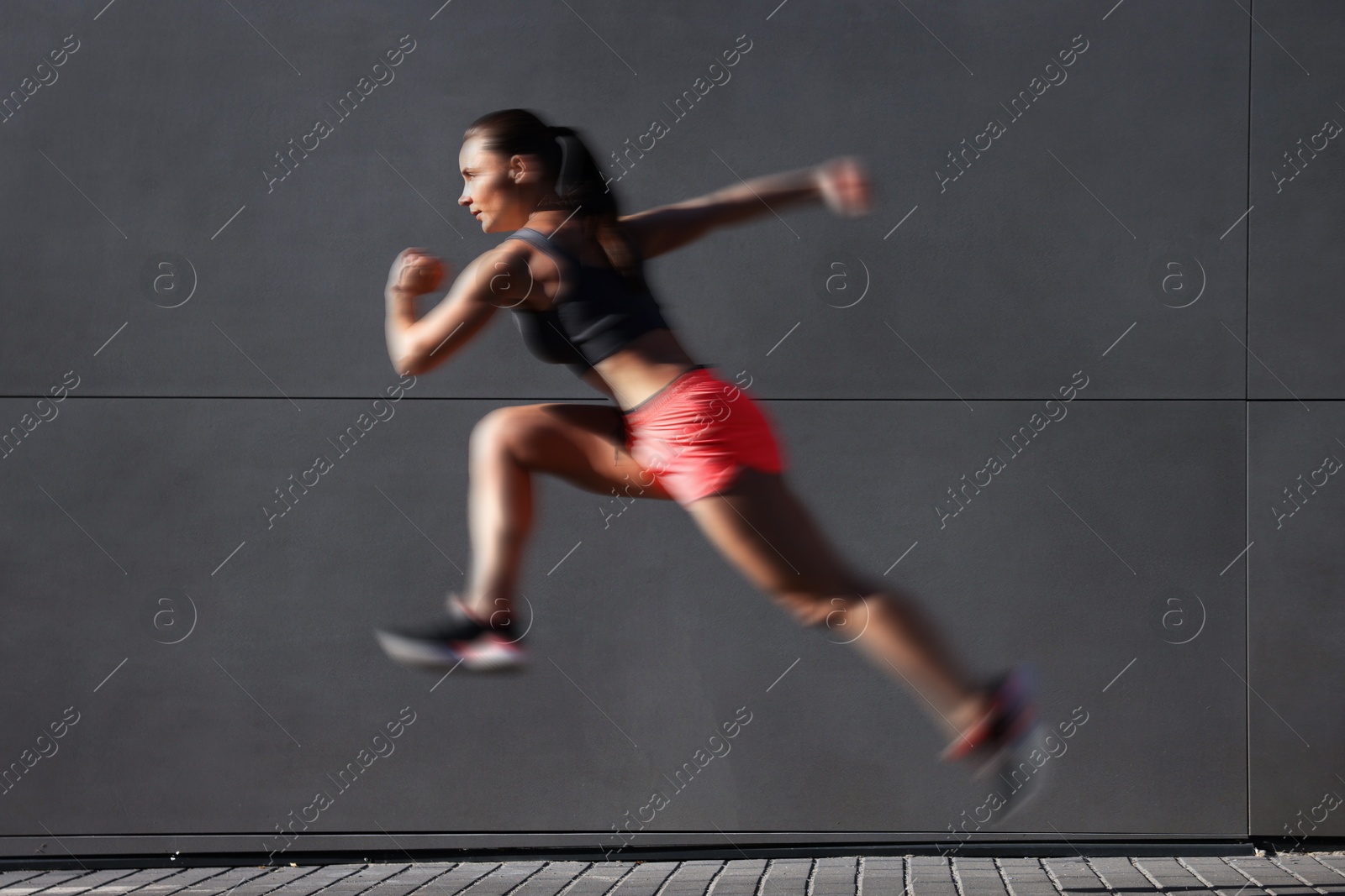 Woman in sportswear running near building outdoors, motion blur effect Image of Woman in sportswear running near building outdoors, motion blur effect