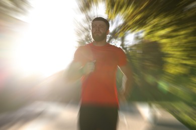 Image of Athletic man running outdoors on sunny day, motion blur effect