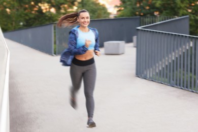 Image of Woman in sportswear running outdoors, motion blur effect