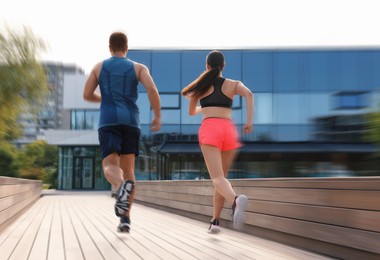 Image of Man and woman in sportswear running outdoors, motion blur effect. Low angle view