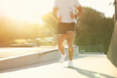Image of Man in sportswear running outdoors on sunny day, motion blur effect