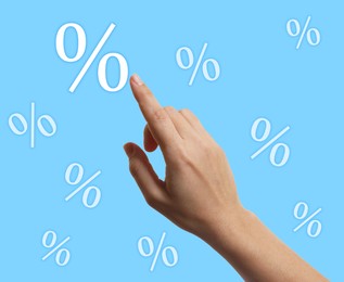 Image of Woman touching virtual percent sign against light blue background, closeup