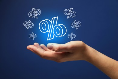 Image of Woman holding virtual percent signs against dark blue background, closeup