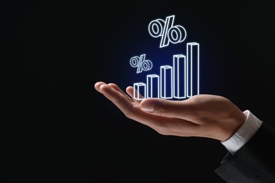 Image of Businessman holding virtual graph and percent signs against black background, closeup