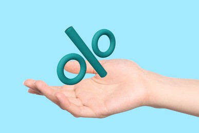 Image of Woman holding virtual percent sign against light blue background, closeup
