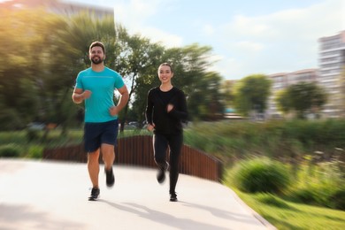 Image of Woman and man in sportswear running outdoors, motion blur effect