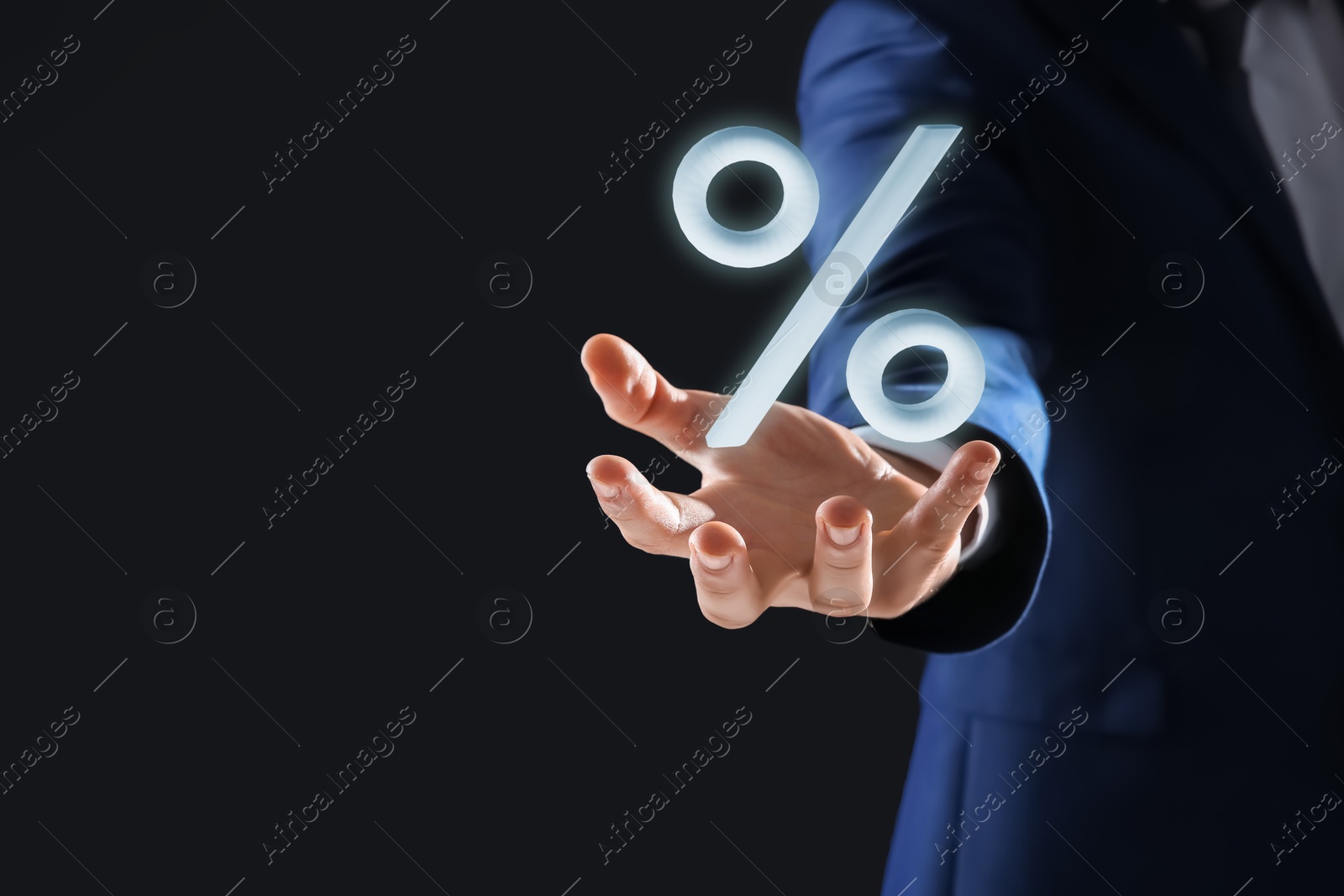 Businessman holding virtual percent sign against black background, closeup Image of Businessman holding virtual percent sign against black background, closeup