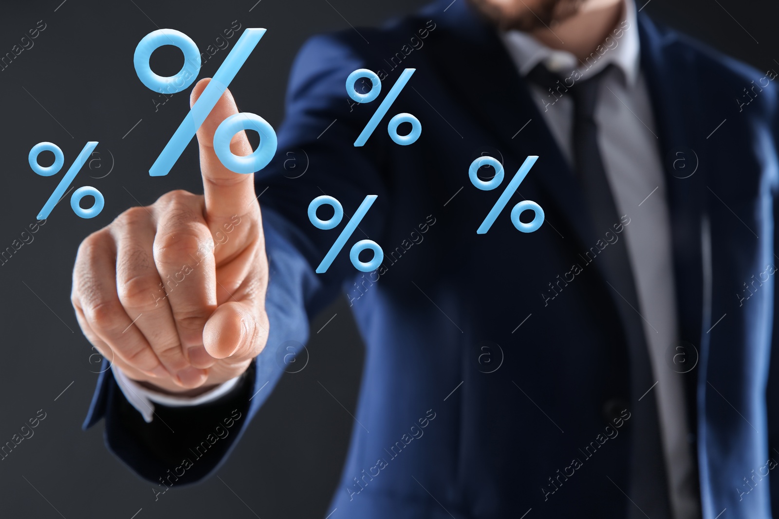 Businessman touching virtual percent sign against dark grey background, closeup Image of Businessman touching virtual percent sign against dark grey background, closeup