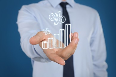 Image of Businessman holding virtual graph and percent signs against blue background, closeup