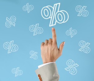 Image of Businessman pointing at virtual percent sign against light blue background, closeup