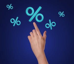Image of Woman touching virtual percent sign against dark blue background, closeup