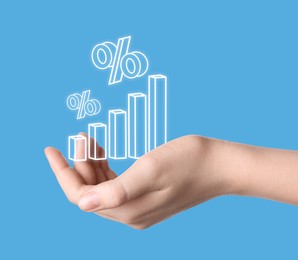 Image of Woman holding virtual graph and percent signs against light blue background, closeup