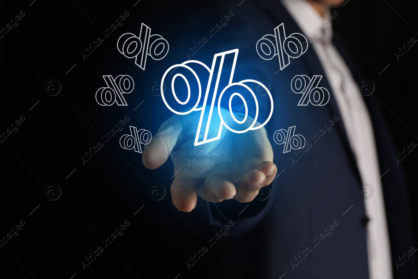 Businessman holding virtual percent sign against black background, closeup Image of Businessman holding virtual percent sign against black background, closeup