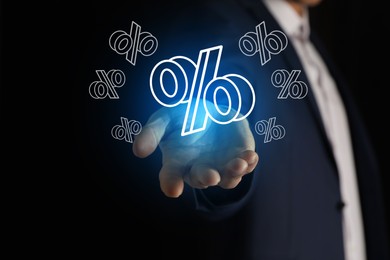 Image of Businessman holding virtual percent sign against black background, closeup