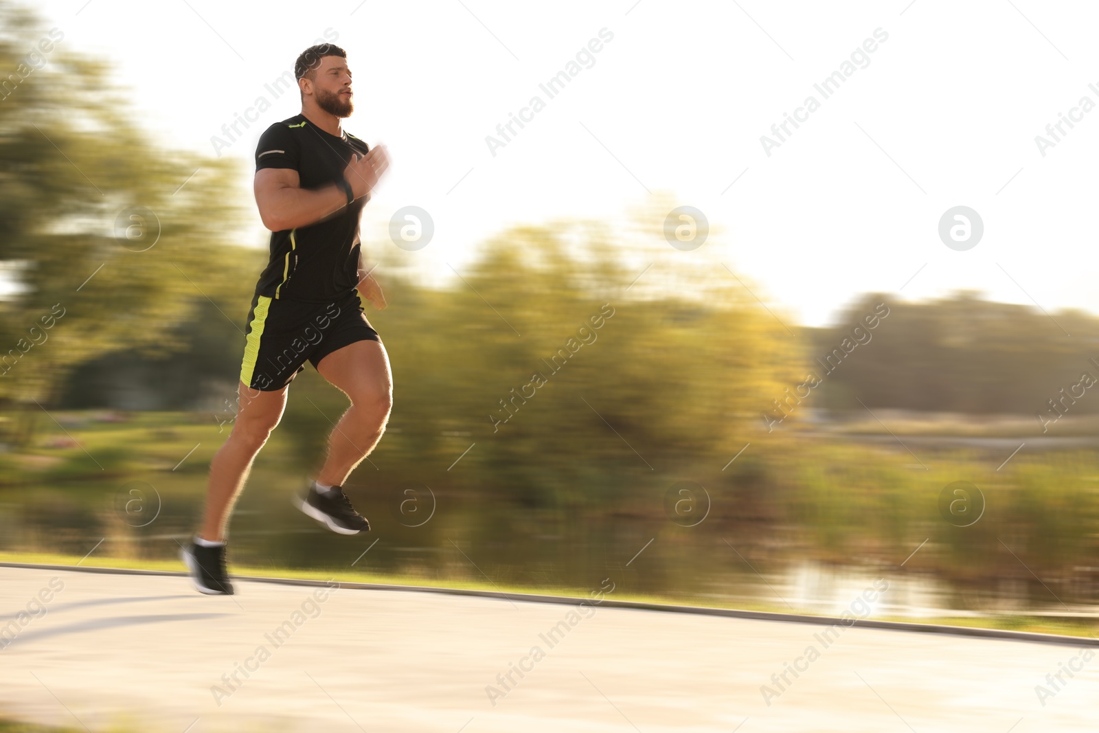 Man in sportswear running outdoors on sunny morning, motion blue effect Image of Man in sportswear running outdoors on sunny morning, motion blue effect
