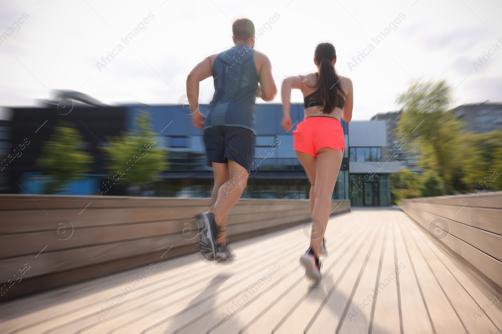 Man and woman in sportswear running outdoors, motion blue effect. Low angle view Image of Man and woman in sportswear running outdoors, motion blue effect. Low angle view