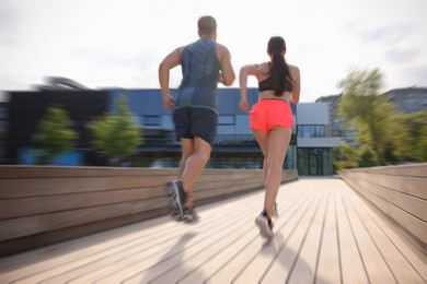 Image of Man and woman in sportswear running outdoors, motion blue effect. Low angle view