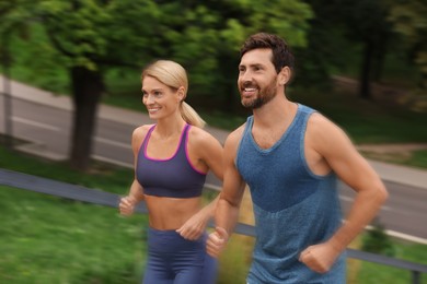 Image of Man and woman in sportswear running outdoors, motion blue effect