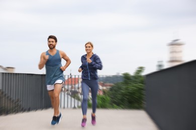 Image of Man and woman in sportswear running outdoors, motion blue effect