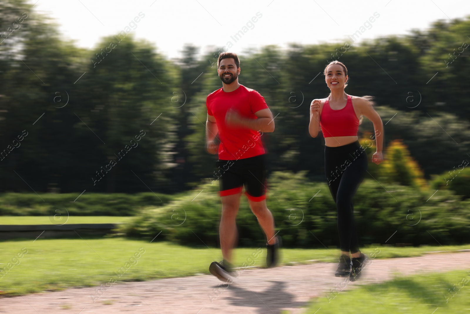 Man and woman in sportswear running outdoors on sunny morning, motion blue effect Image of Man and woman in sportswear running outdoors on sunny morning, motion blue effect